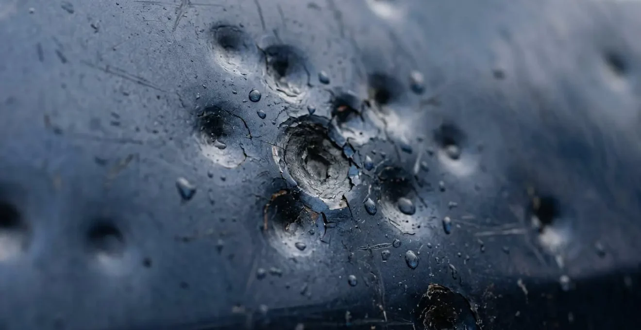 Gros plan sur des impacts de grêle sur une carrosserie de voiture montrant les dommages nécessitant une expertise